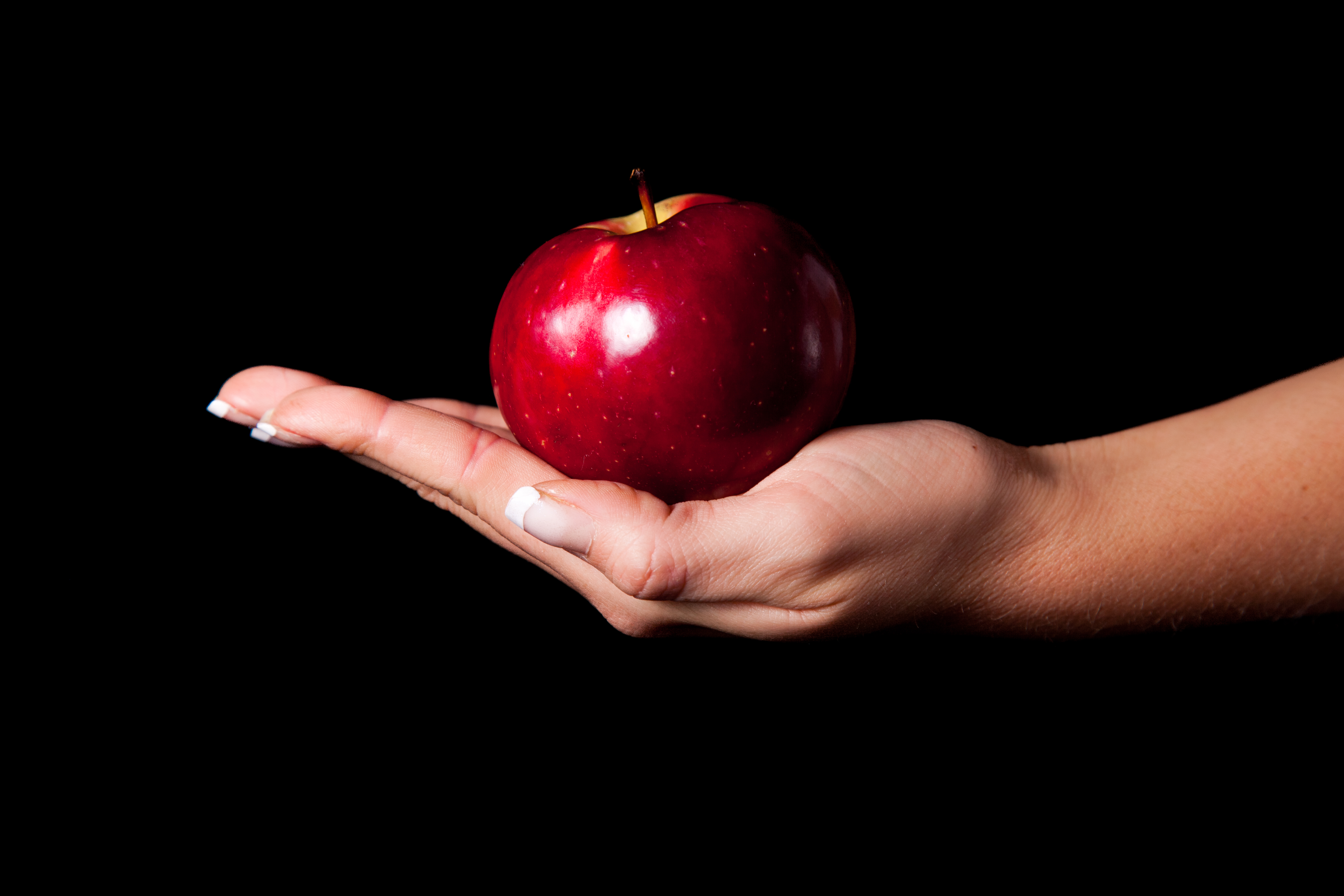 Кинуть яблоко. Яблоко в руке. Яблоко на темном фоне. Яблоко в руке на темном фоне. Красное яблоко в руке.